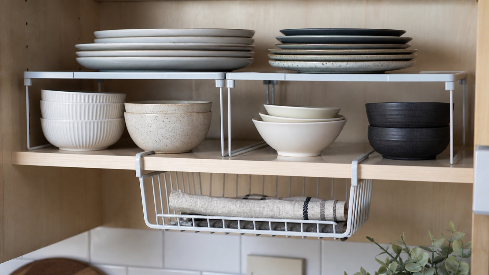 Shelf risers doubling cabinet space with plates on top and bowls beneath