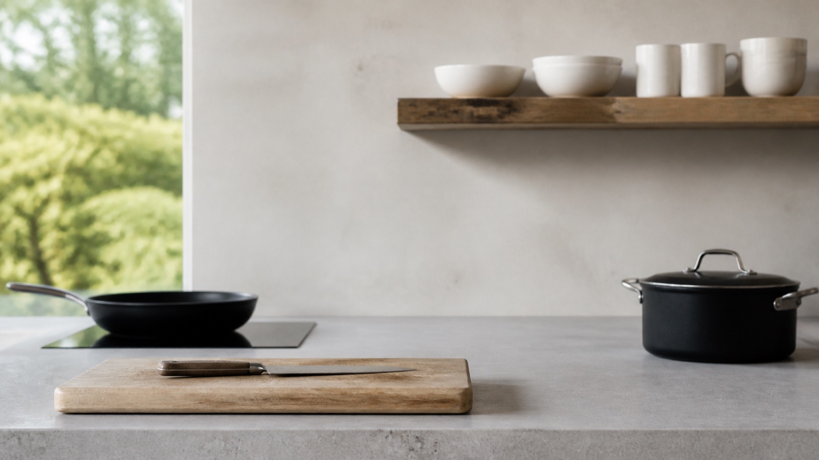Minimalist kitchen with a knife, cutting board, skillet, pot, and a few bowls