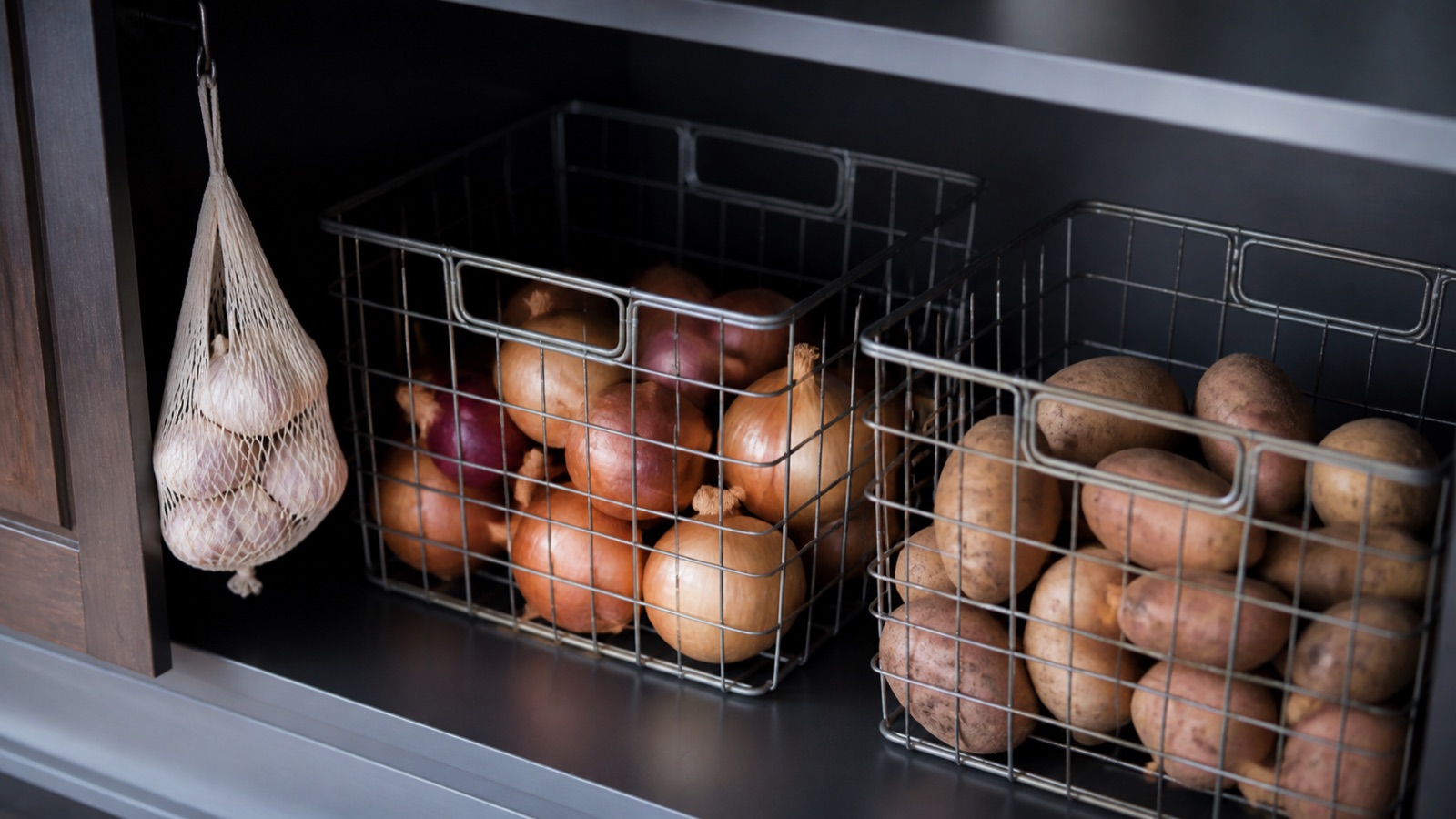 Onions and potatoes in separate ventilated wire baskets in a cool cabinet